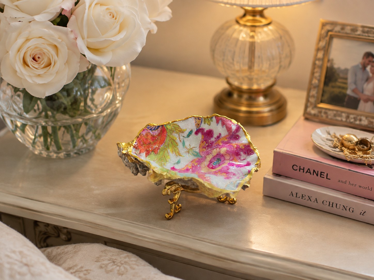 Gold-edged floral oyster shell displayed beside white roses